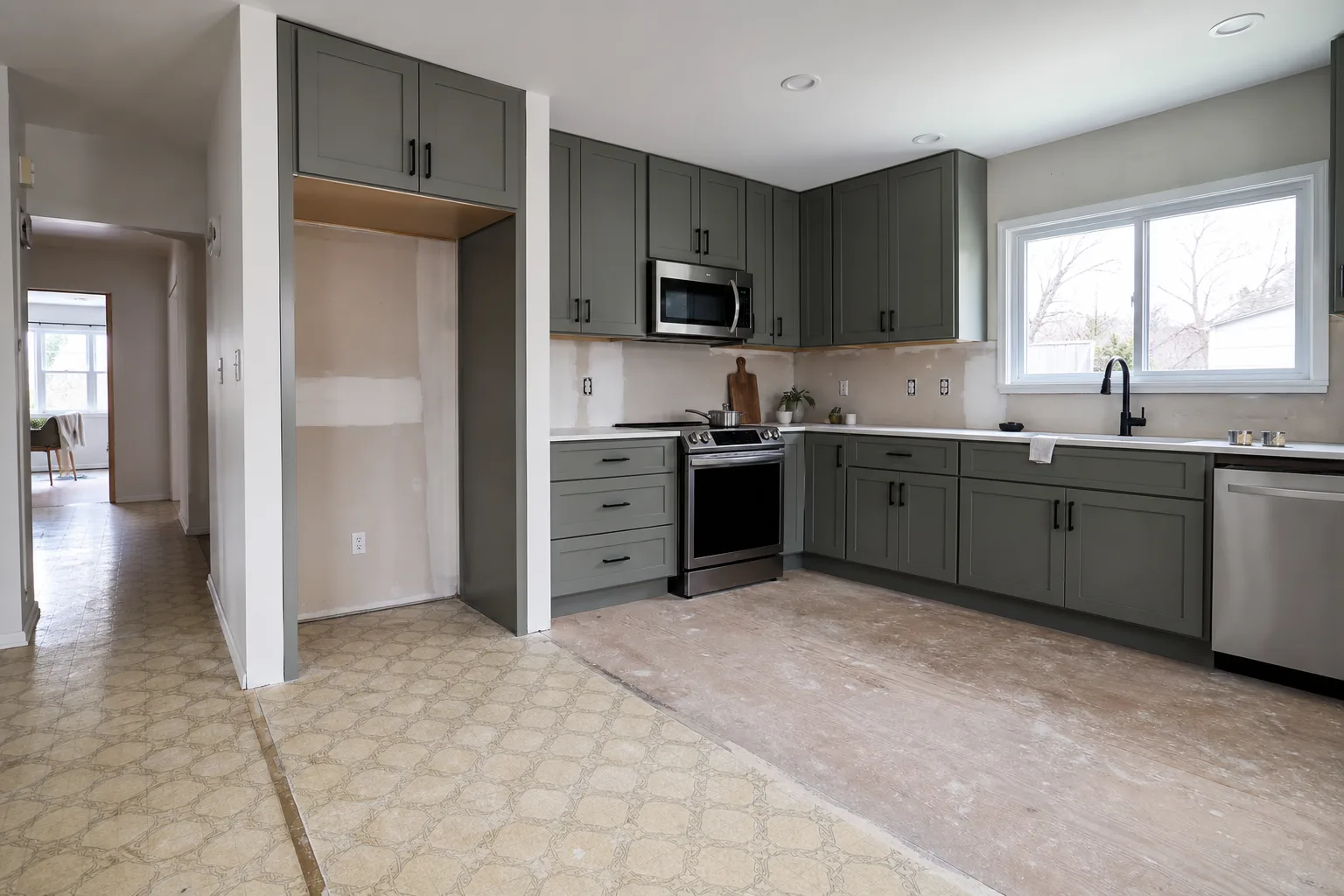 A half-renovated kitchen in a single-story suburban house, with new cabinets installed on one wall and the original flooring still visible near the refrigera...